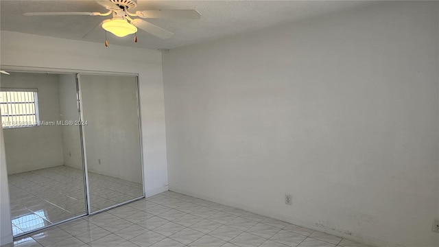 unfurnished bedroom with light tile patterned floors, ceiling fan, and a closet