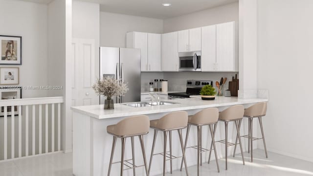 kitchen with kitchen peninsula, appliances with stainless steel finishes, a kitchen breakfast bar, white cabinetry, and sink