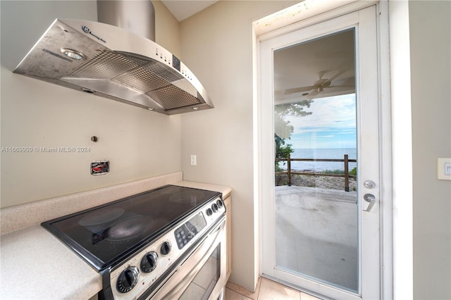 kitchen featuring a water view, stainless steel electric range, light tile patterned floors, ventilation hood, and ceiling fan