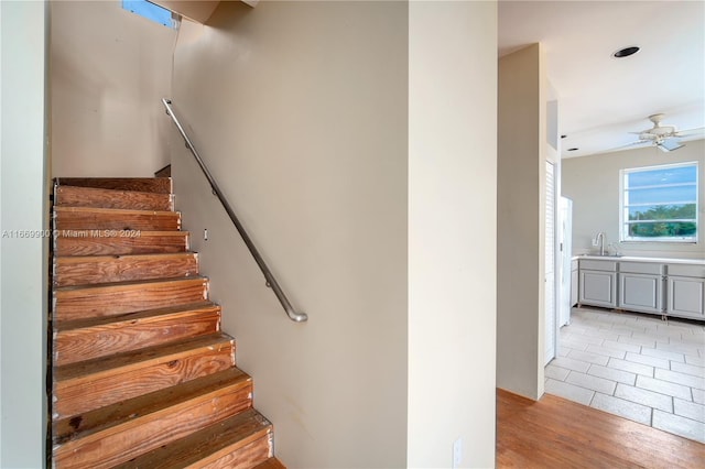 staircase with ceiling fan, hardwood / wood-style floors, and sink