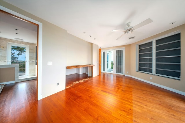 unfurnished living room featuring ceiling fan, hardwood / wood-style flooring, and built in shelves