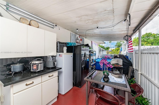 kitchen featuring white refrigerator, black fridge with ice dispenser, white cabinetry, and concrete floors