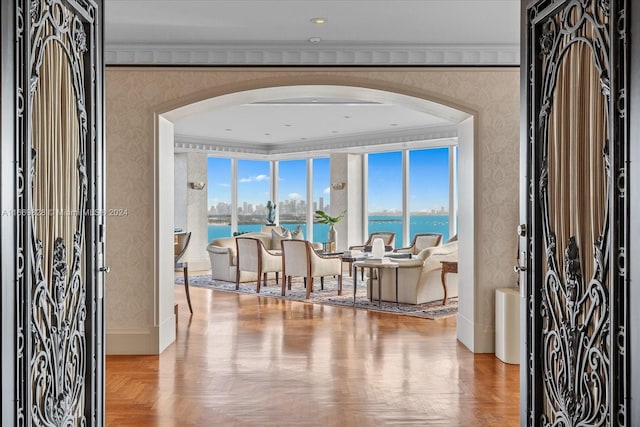 foyer featuring a water view, crown molding, and parquet floors