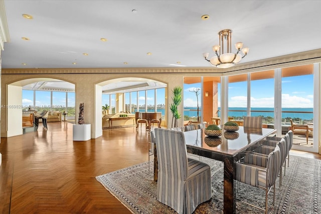 dining room with parquet flooring, an inviting chandelier, and a water view