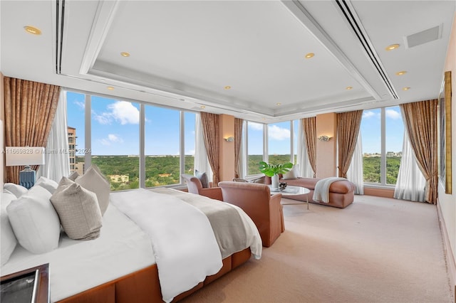 bedroom with a tray ceiling, light colored carpet, and floor to ceiling windows