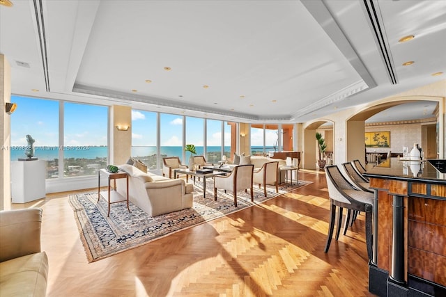 living room featuring dark parquet floors, a tray ceiling, and ornamental molding