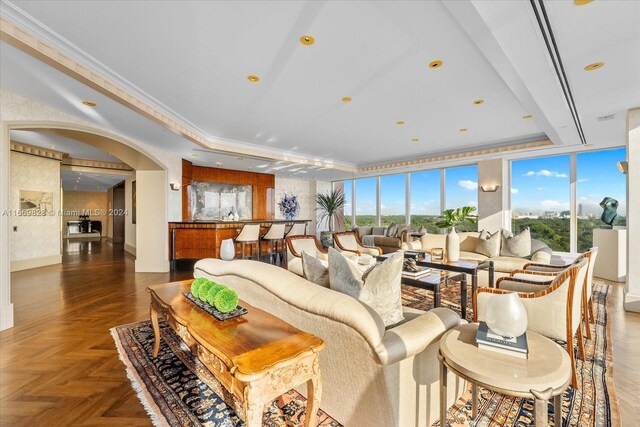 living room with crown molding, dark parquet floors, and a raised ceiling