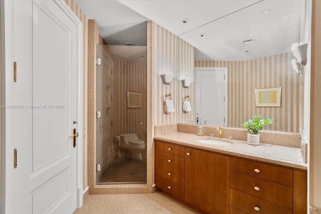 bathroom with a shower with door, vanity, and toilet