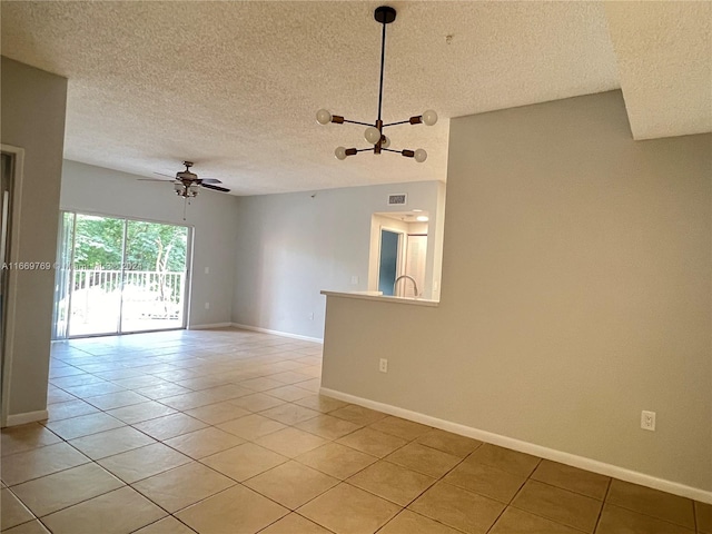 tiled spare room with ceiling fan with notable chandelier and a textured ceiling