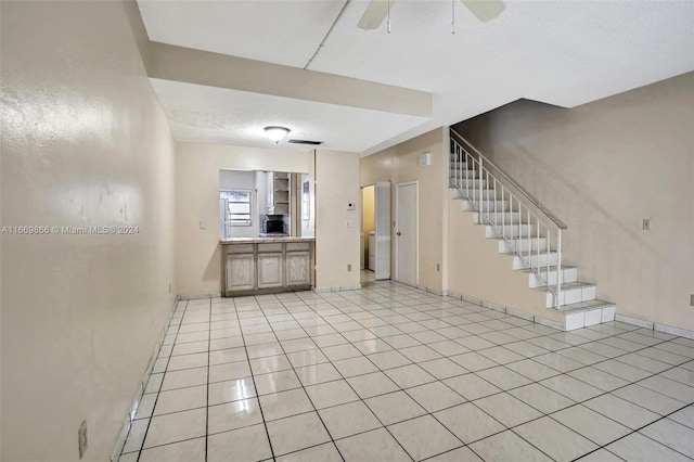 unfurnished living room with a textured ceiling, ceiling fan, and light tile patterned floors