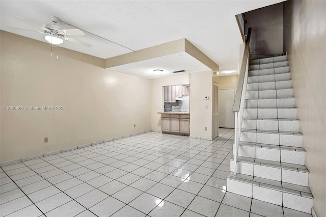 interior space with a textured ceiling, ceiling fan, and light tile patterned floors