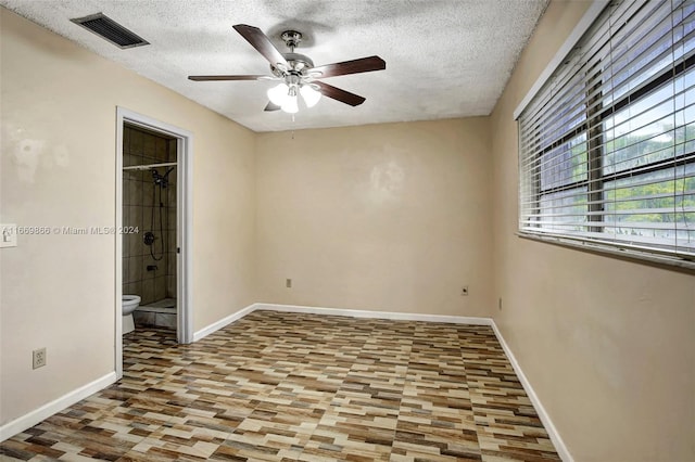 unfurnished bedroom featuring wood-type flooring, a textured ceiling, connected bathroom, and ceiling fan