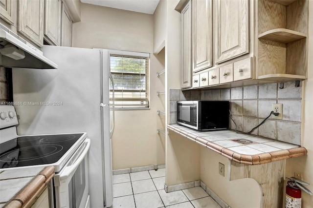 kitchen with white electric range, tile countertops, backsplash, and light tile patterned floors