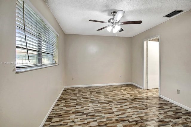 unfurnished room with ceiling fan and a textured ceiling