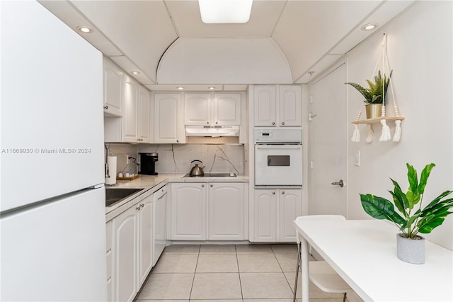 kitchen featuring white cabinets, light tile patterned floors, white appliances, and tasteful backsplash