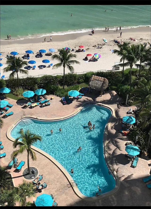 view of swimming pool featuring a beach view, a patio, and a water view