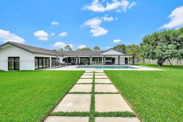 back of property with a fenced in pool, a patio area, and a lawn