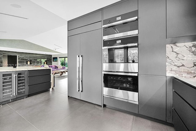 kitchen with lofted ceiling, backsplash, double oven, paneled fridge, and beverage cooler