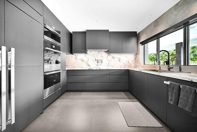 kitchen with sink, gray cabinetry, tasteful backsplash, dishwasher, and stainless steel double oven