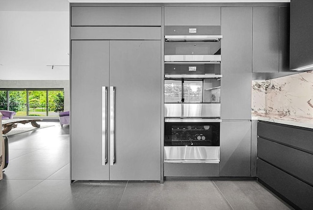 kitchen with gray cabinetry, double oven, tasteful backsplash, and paneled built in fridge