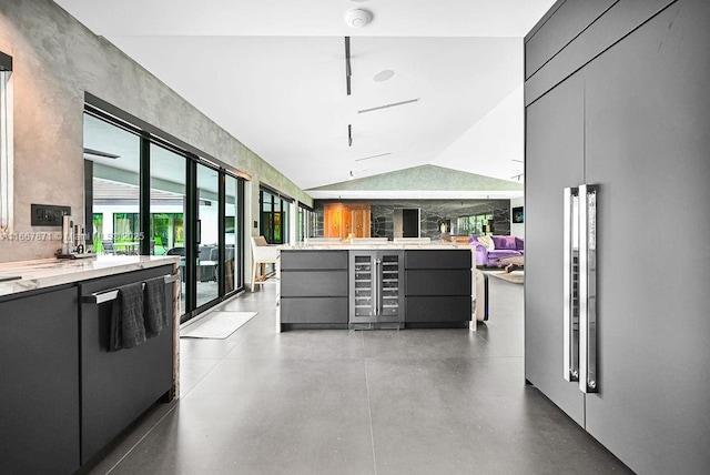 kitchen with vaulted ceiling, gray cabinetry, dishwashing machine, concrete floors, and paneled built in refrigerator