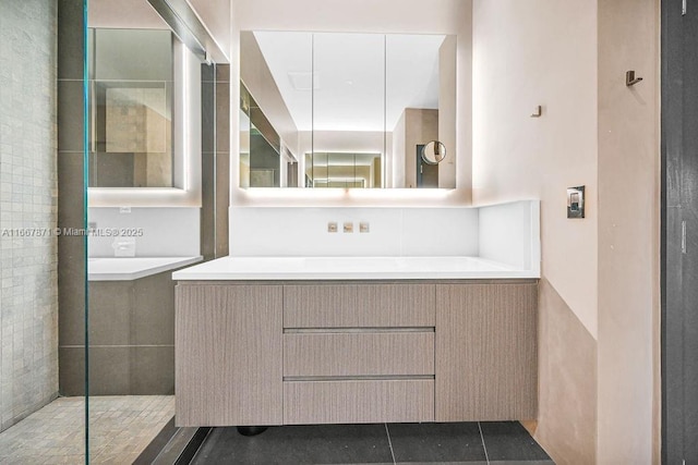 bathroom with tile patterned floors, vanity, and a tile shower