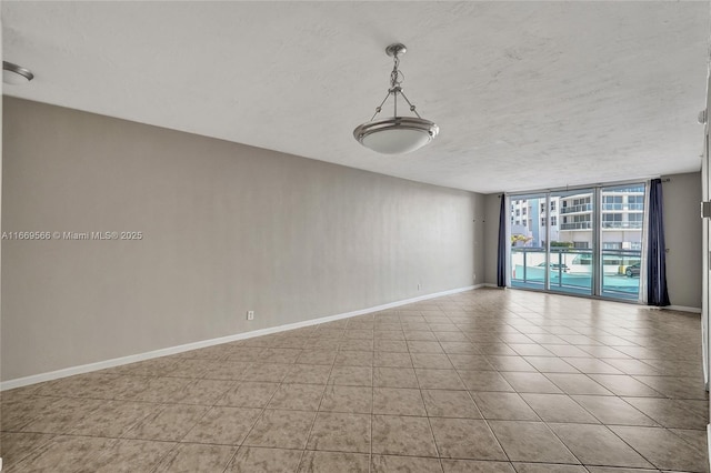 unfurnished room featuring expansive windows, light tile patterned flooring, a textured ceiling, and baseboards