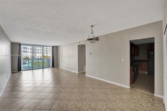 spare room featuring light tile patterned floors, a wall of windows, a textured ceiling, and baseboards