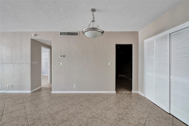 unfurnished room featuring visible vents, a textured ceiling, baseboards, and light tile patterned floors