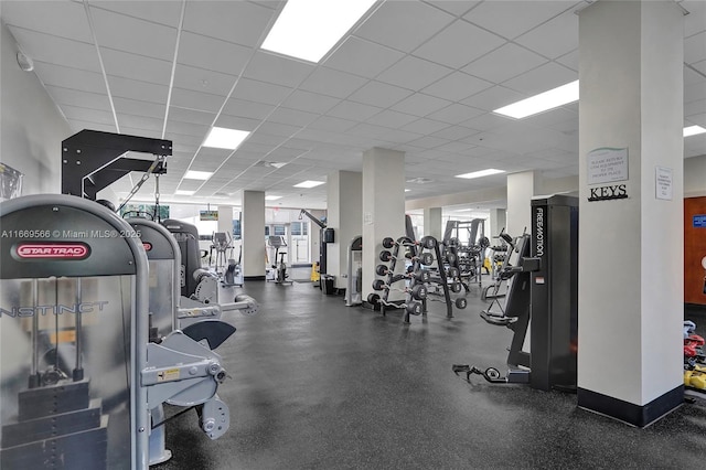 exercise room with baseboards, a drop ceiling, and a healthy amount of sunlight