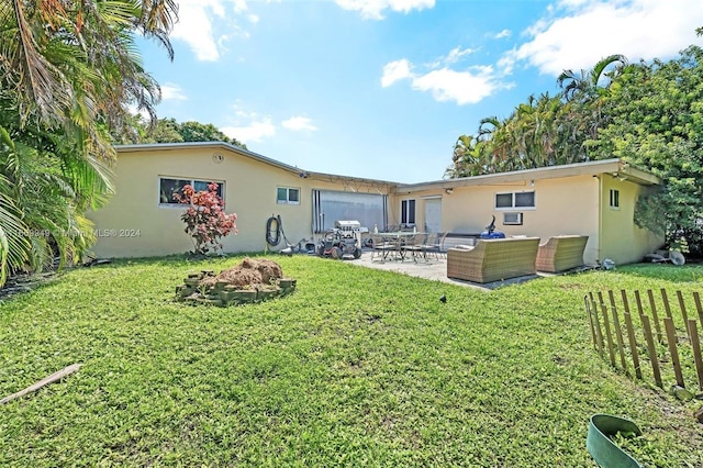 back of property featuring an outdoor living space with a fire pit, a lawn, a patio, and stucco siding