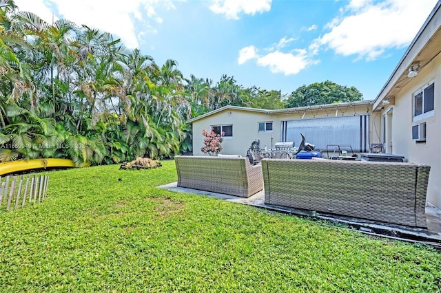 rear view of property featuring a lawn, an outdoor living space, and stucco siding