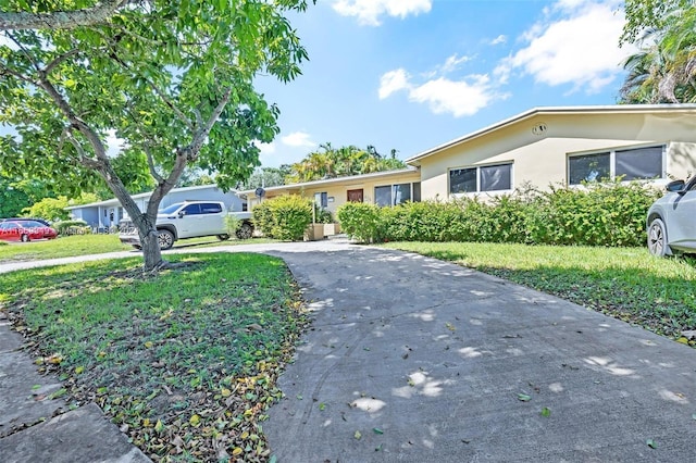 ranch-style home featuring stucco siding, aphalt driveway, and a front lawn