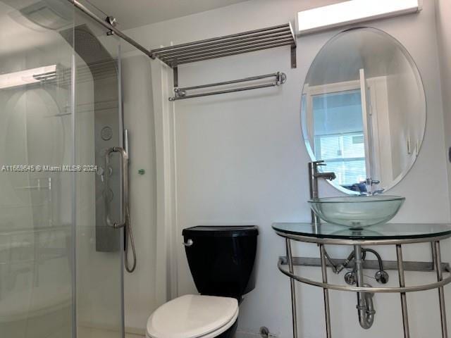 bathroom featuring toilet and a shower with door