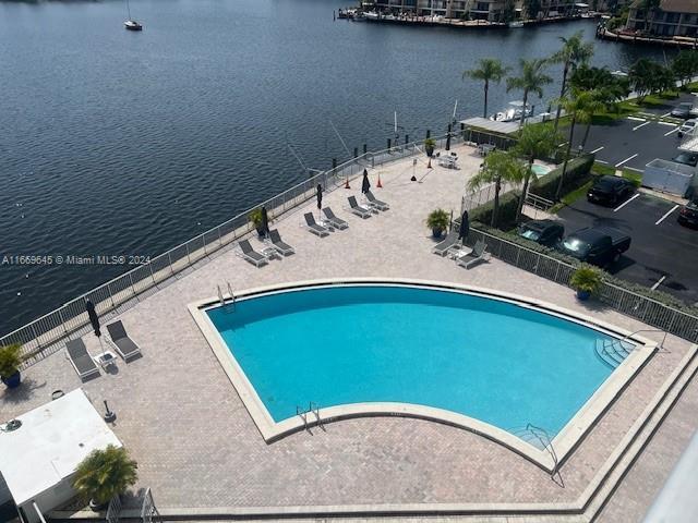 view of pool featuring a water view and a patio