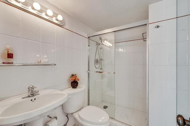 full bath featuring tile walls, a sink, a shower stall, and toilet
