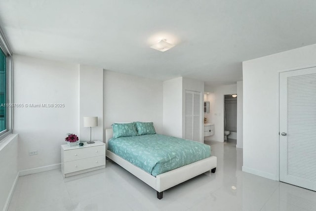 tiled bedroom with baseboards and connected bathroom