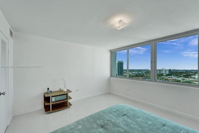 unfurnished bedroom featuring tile patterned floors, a city view, visible vents, and baseboards