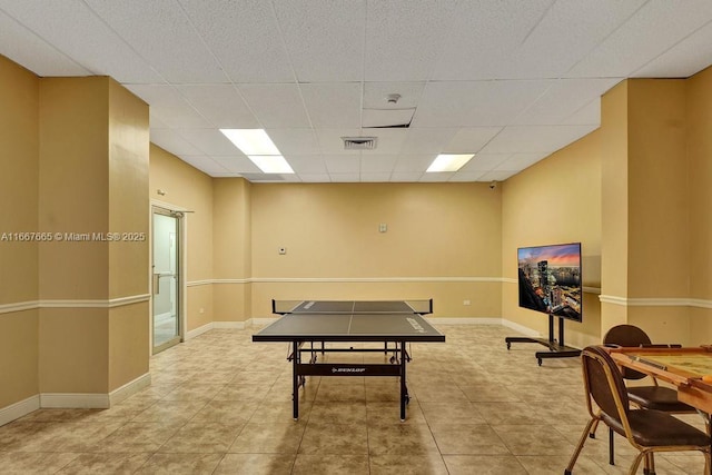 rec room featuring baseboards, tile patterned flooring, a drop ceiling, and visible vents