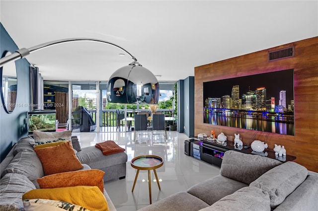 living room with wooden walls, light tile patterned floors, and floor to ceiling windows