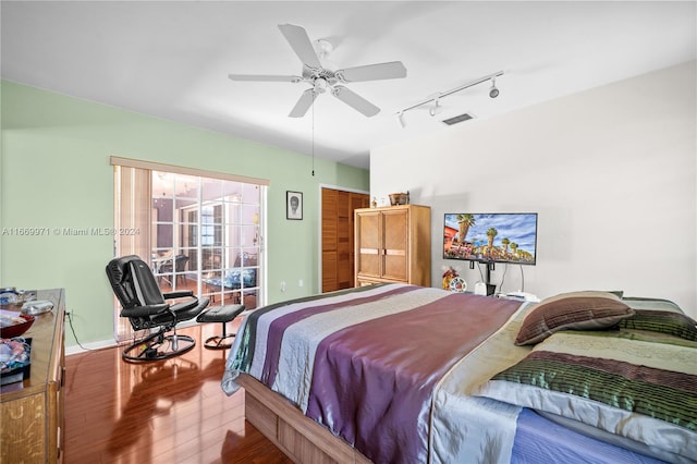 bedroom with track lighting, wood-type flooring, and ceiling fan