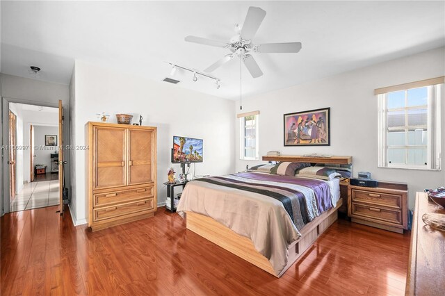 bedroom with rail lighting, ceiling fan, and hardwood / wood-style floors