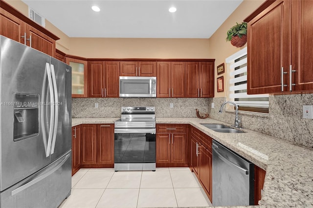 kitchen featuring decorative backsplash, light stone counters, appliances with stainless steel finishes, and sink