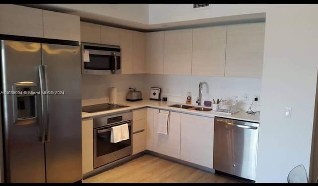 kitchen with light hardwood / wood-style floors, appliances with stainless steel finishes, and sink