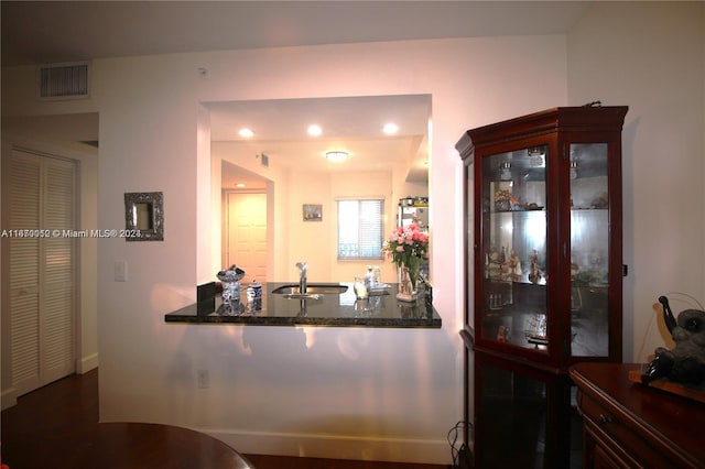 bar with dark stone countertops, sink, and hardwood / wood-style floors