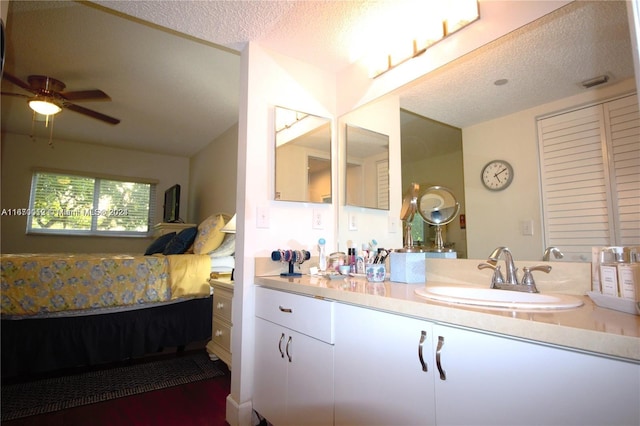 bathroom with ceiling fan, a textured ceiling, and vanity