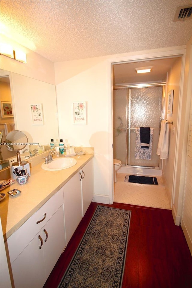 bathroom featuring vanity, toilet, a textured ceiling, walk in shower, and hardwood / wood-style floors