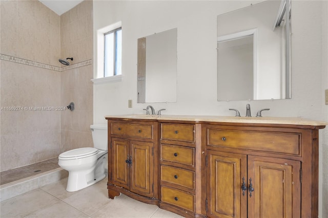 bathroom with a tile shower, tile patterned flooring, vanity, and toilet