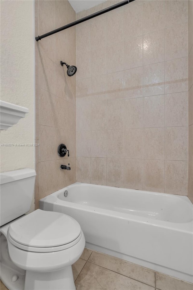 bathroom with tile patterned floors, tiled shower / bath, and toilet