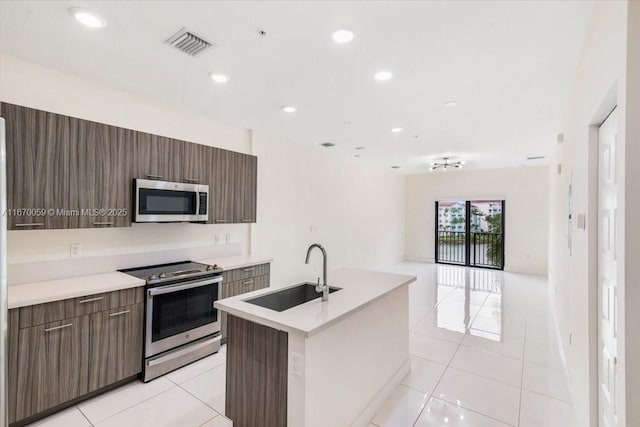 kitchen featuring sink, light tile patterned flooring, a center island with sink, and appliances with stainless steel finishes